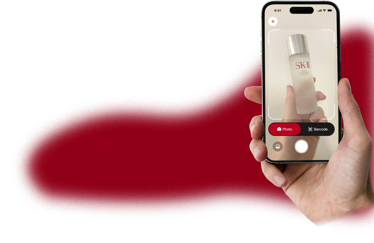A red gradient backdrop behind a hand holding a phone scanning a skincare product